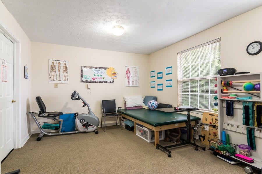 A therapy room equipped with exercise gear, a massage table, and educational posters on the walls.