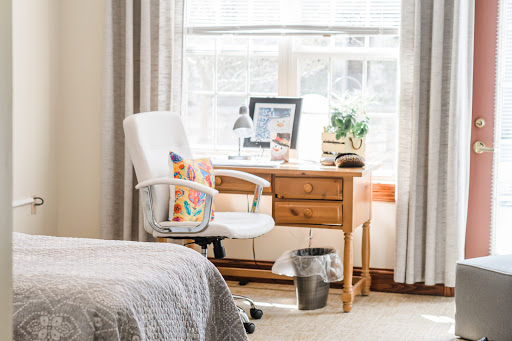 A cozy workspace featuring a wooden desk, comfortable chair, and natural light from the window.