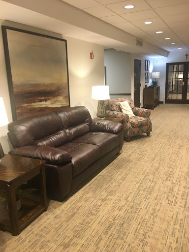 A cozy living room area featuring a leather couch, an armchair, and stylish lamps.