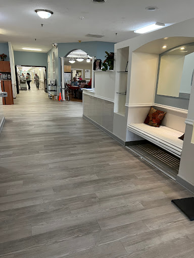 A modern lobby area featuring a cozy bench, wooden flooring, and plants, inviting guests to relax.