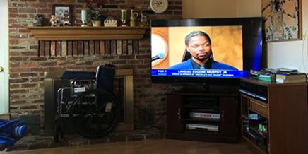 A living room with a TV showing a news broadcast next to a fireplace.