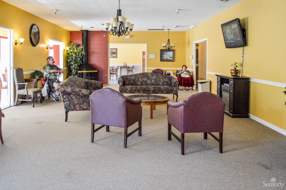A cozy living area with sofas, chairs, a table, and a television.