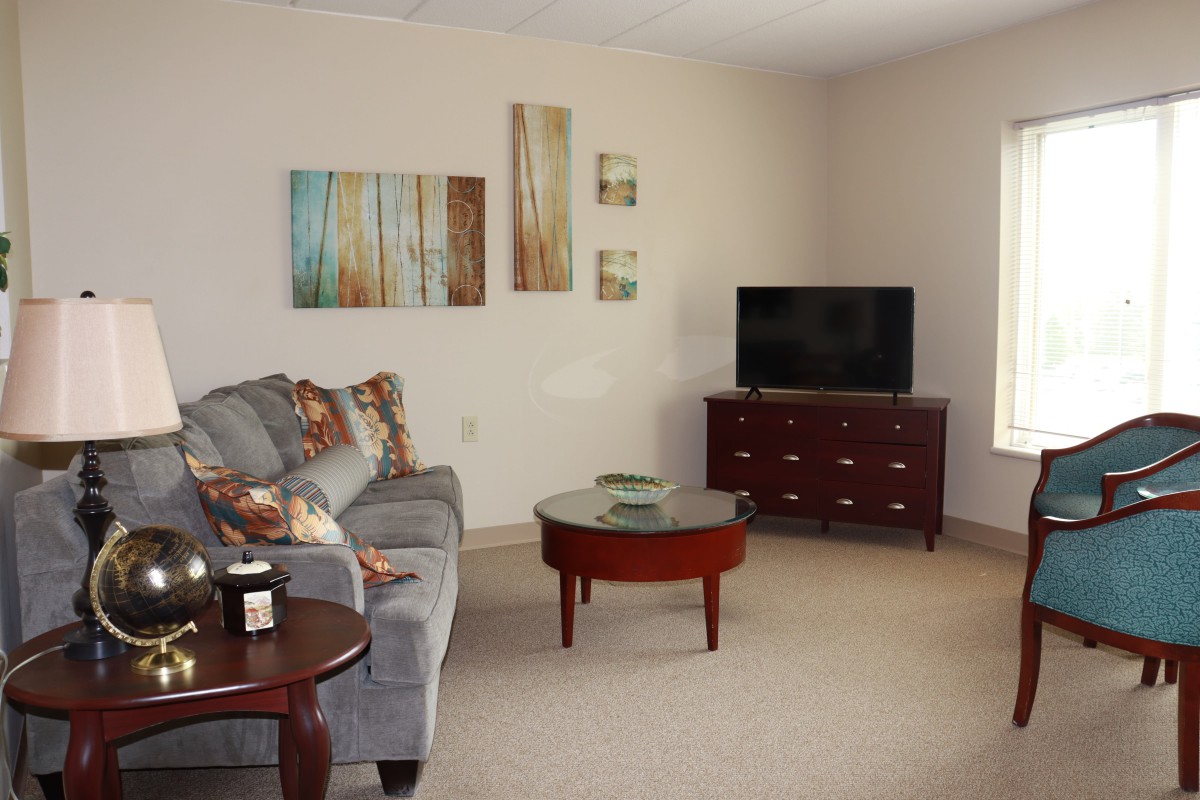 A cozy living room with a sofa, coffee table, and a TV, complemented by wall artwork.
