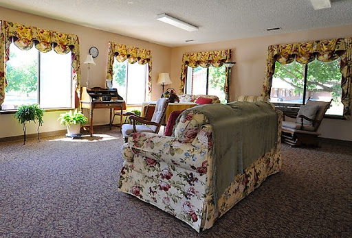 A cozy living room filled with natural light, featuring floral-patterned furniture and elegant window treatments.