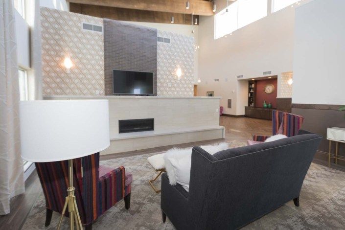 A modern living room with contemporary furniture, a wall-mounted television, and a built-in fireplace.