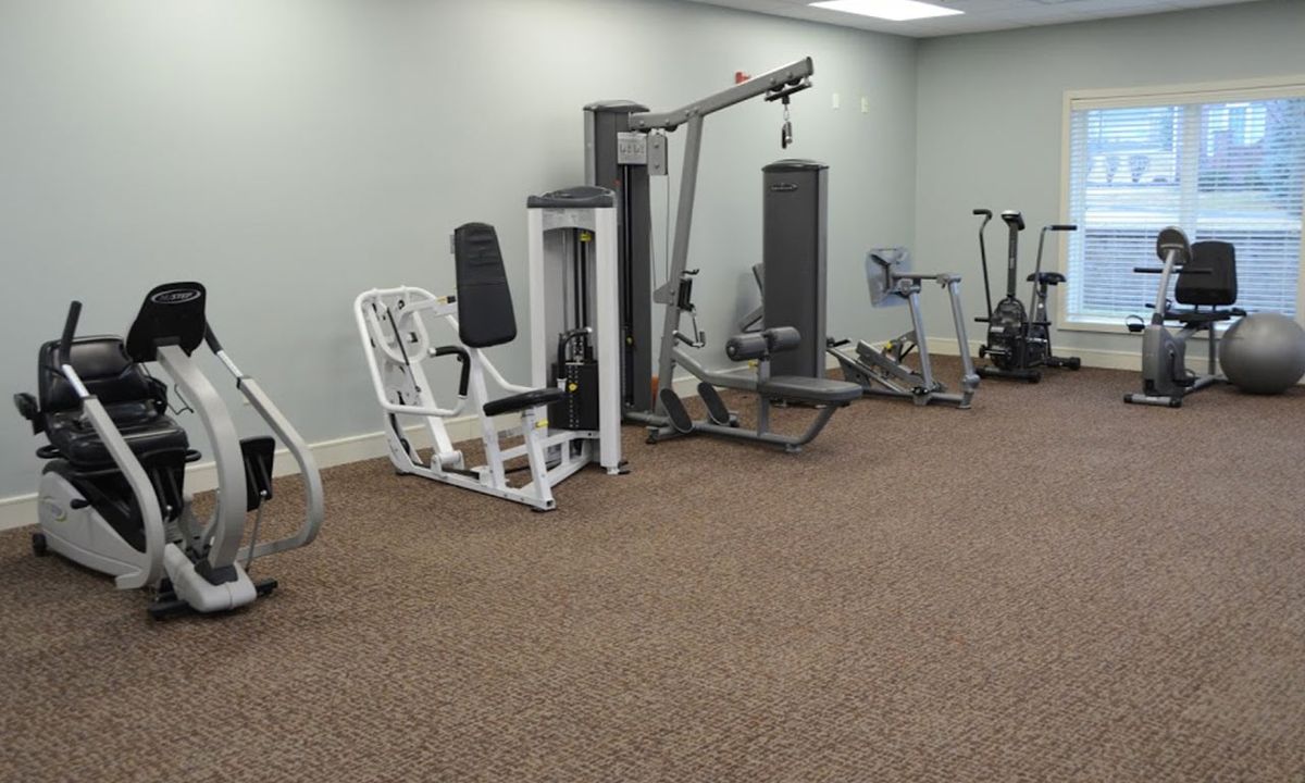 A gym with various exercise equipment and workout machines.