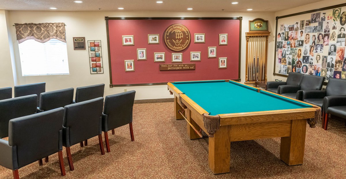 A cozy game room featuring a billiards table, wall decor, and comfortable seating.