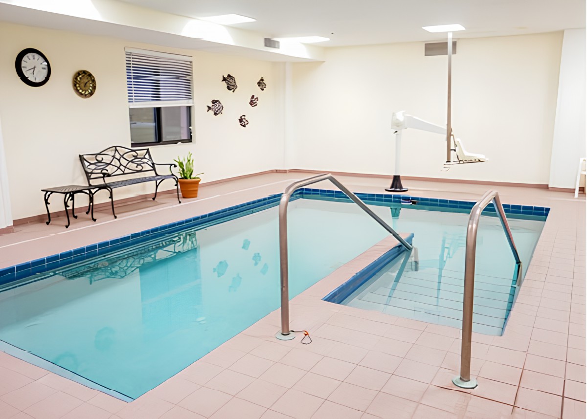 An indoor swimming pool equipped with a bench and a lift for accessibility.