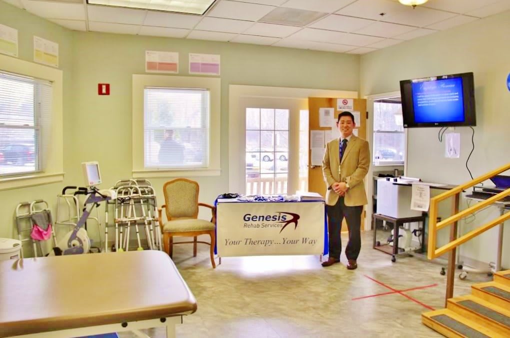 A professional standing in a medical clinic with various equipment and a welcoming setup.