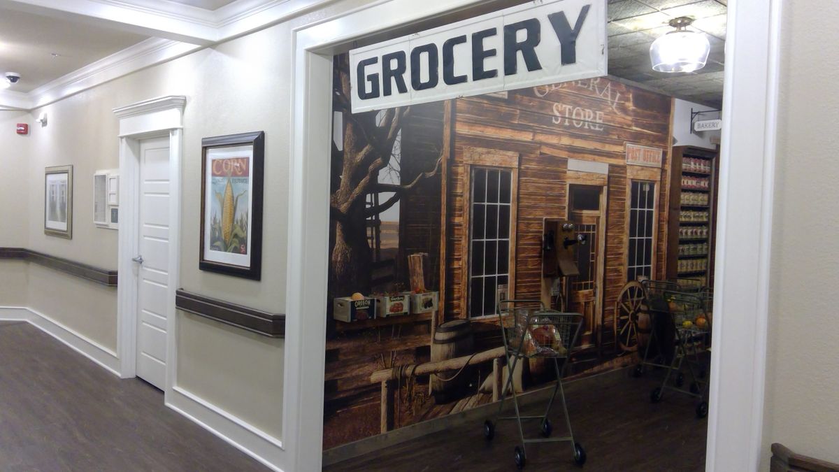 A mural of a vintage grocery store scene with a shopping cart placed nearby.