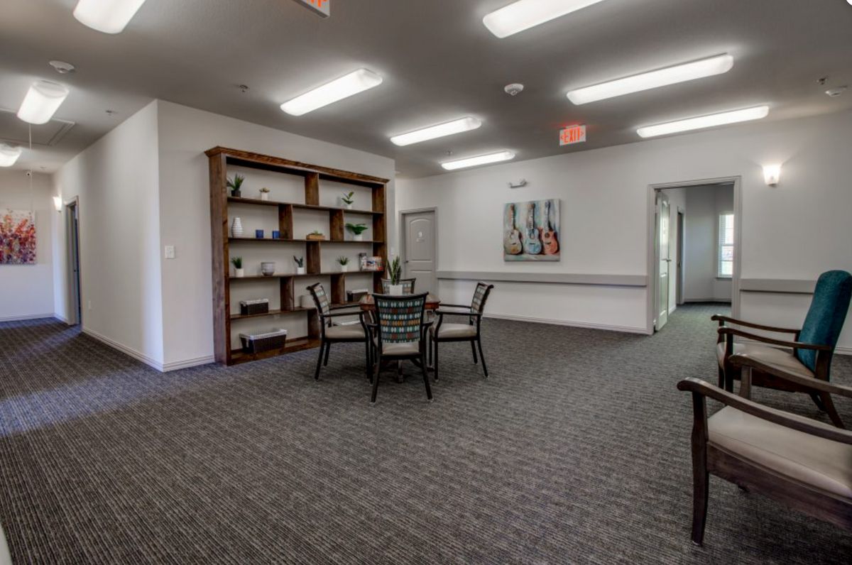 A well-lit room with a table and chairs, a bookshelf, and artwork adorning the wall.