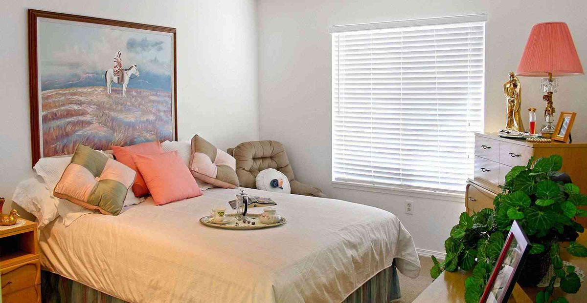A cozy bedroom with a neatly made bed and decorative pillows.