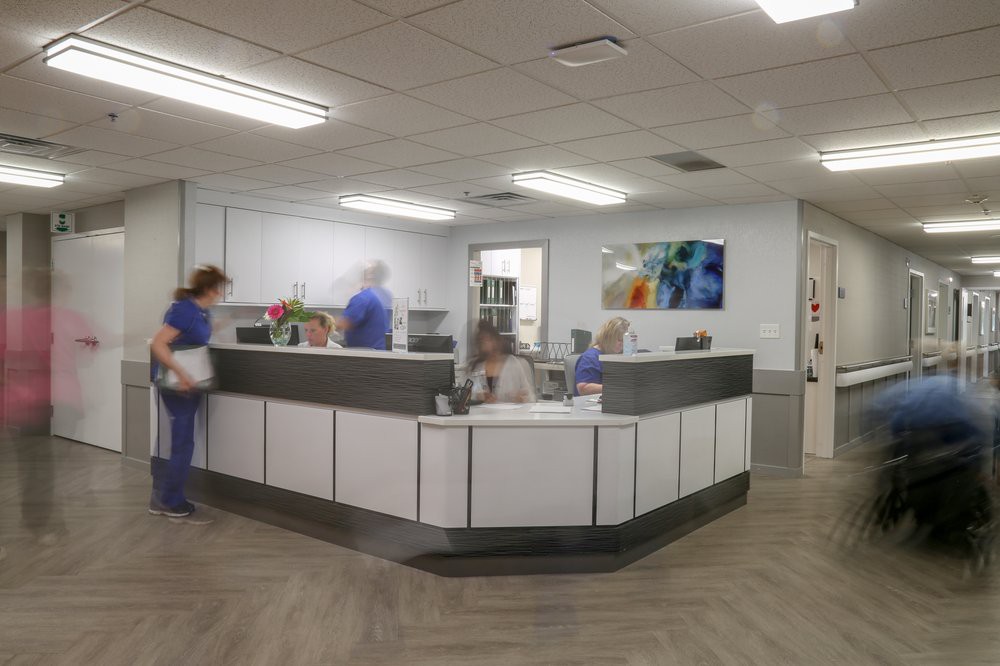 A busy reception area in a medical clinic with staff and patients.