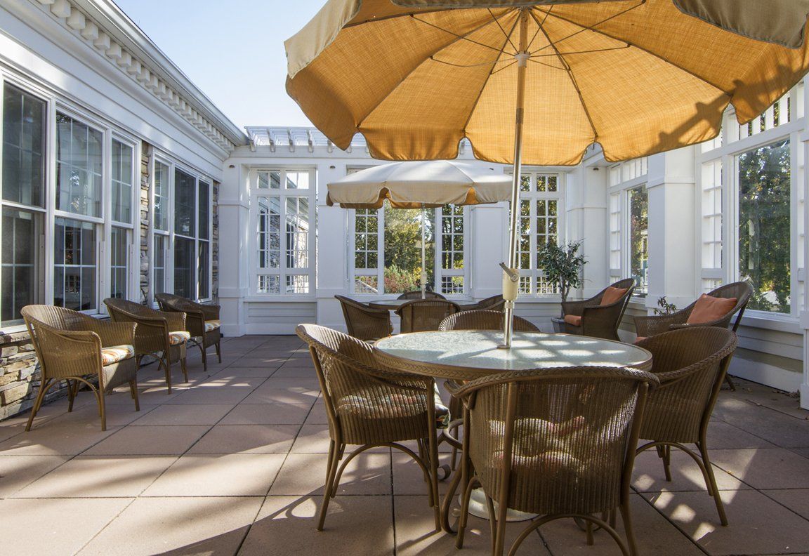 A sunny patio with wicker furniture and large umbrellas providing shade.