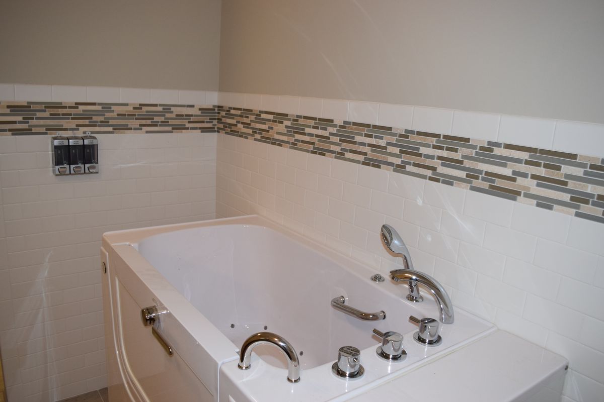 A modern bathroom with a built-in bathtub and decorative tile accents.