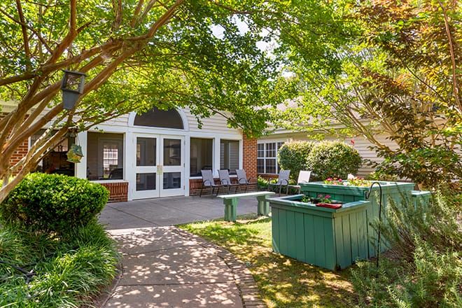A tranquil outdoor garden area with benches, trees, and a building in the background.