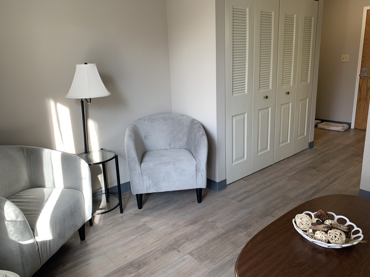 A cozy living room corner with chairs, a lamp, and a side table.