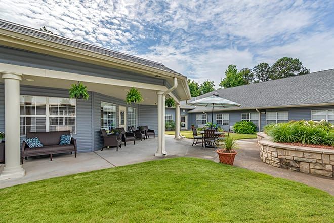 A cozy outdoor patio area in a residential setting, featuring garden furniture and umbrellas under a cloudy sky.
