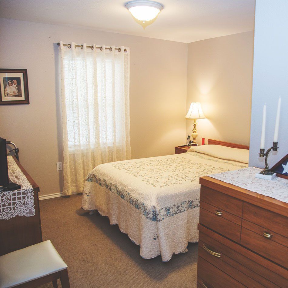 Cozy bedroom with a bed, dresser, and lamp.