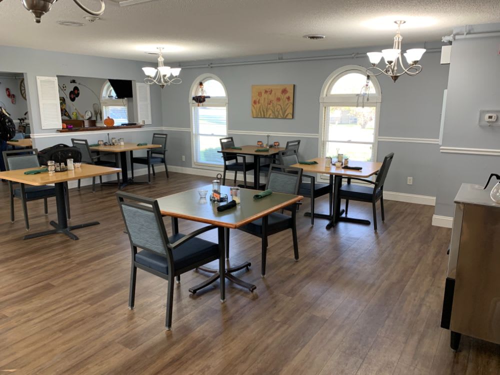 A cozy dining area with neatly arranged tables and chairs, featuring elegant lighting and decor.