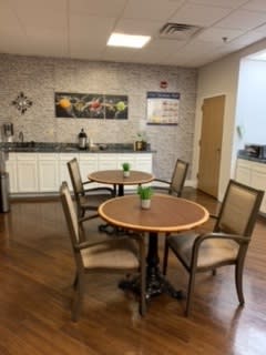 A cozy breakroom with tables and chairs, complete with a kitchenette area.