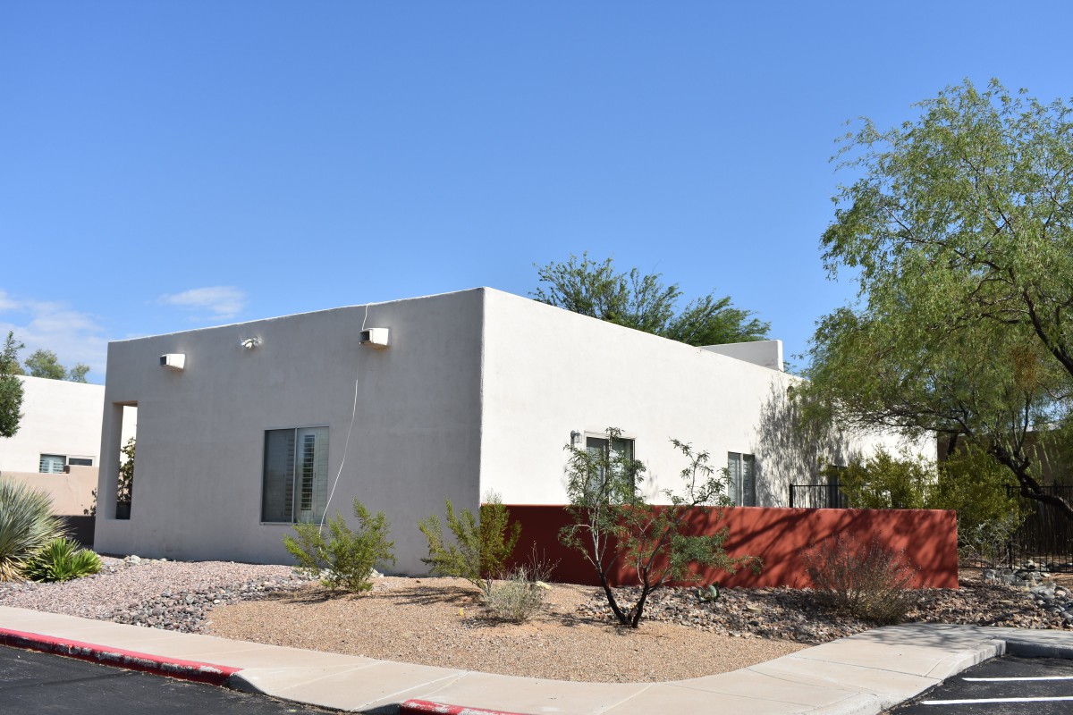 A modern white building set against a clear blue sky with desert landscaping.