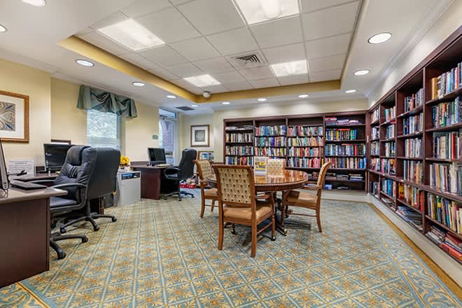 A cozy library room with bookshelves, a round table, and computers for study.
