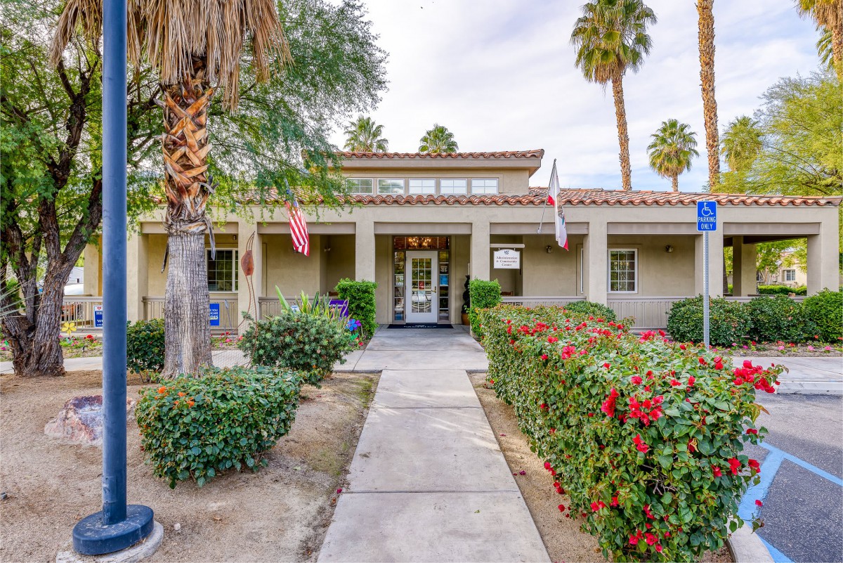 A building entrance surrounded by palm trees and well-maintained landscaping.