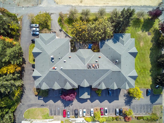 Aerial view of a large building with a parking lot and surrounding greenery.