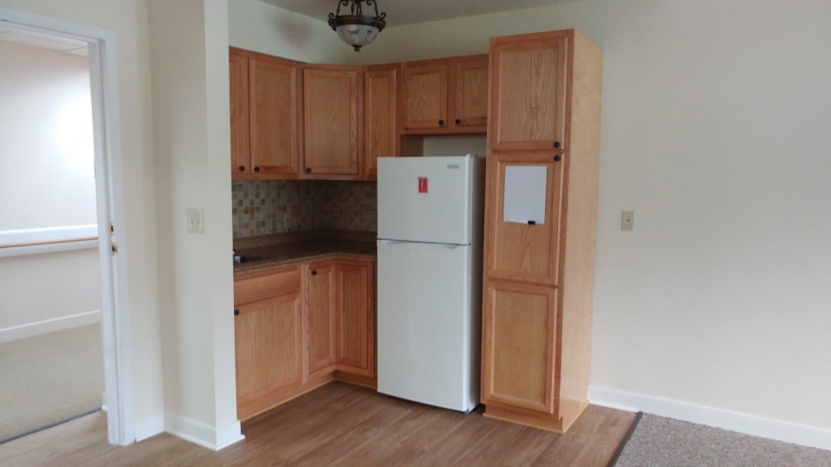 A compact kitchen with wooden cabinets and a refrigerator.