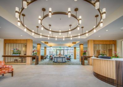 A modern, spacious lobby with elegant circular chandeliers and a reception desk.