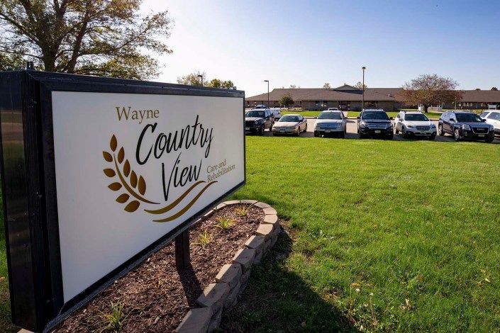 A sunny day view of a parking lot in front of a building with a sign reading 'Wayne Country View'.