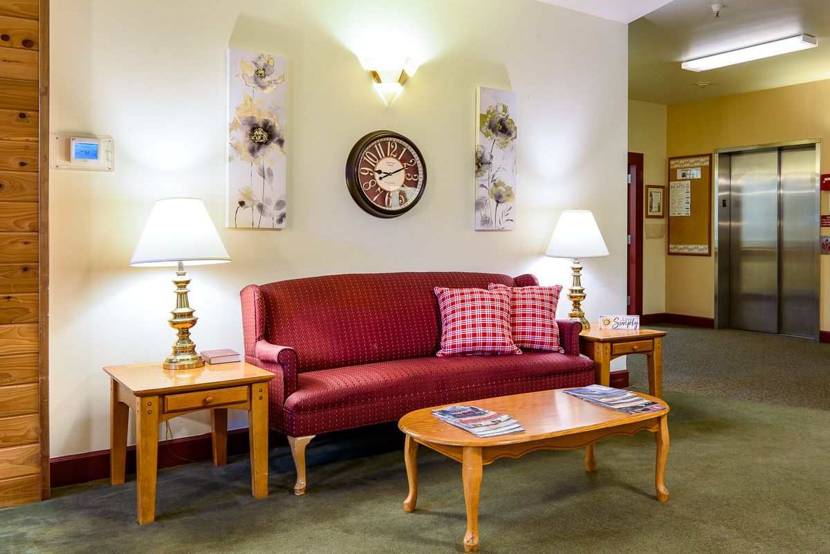 A cozy living room with a red sofa, wooden coffee table, and decorative lamps.