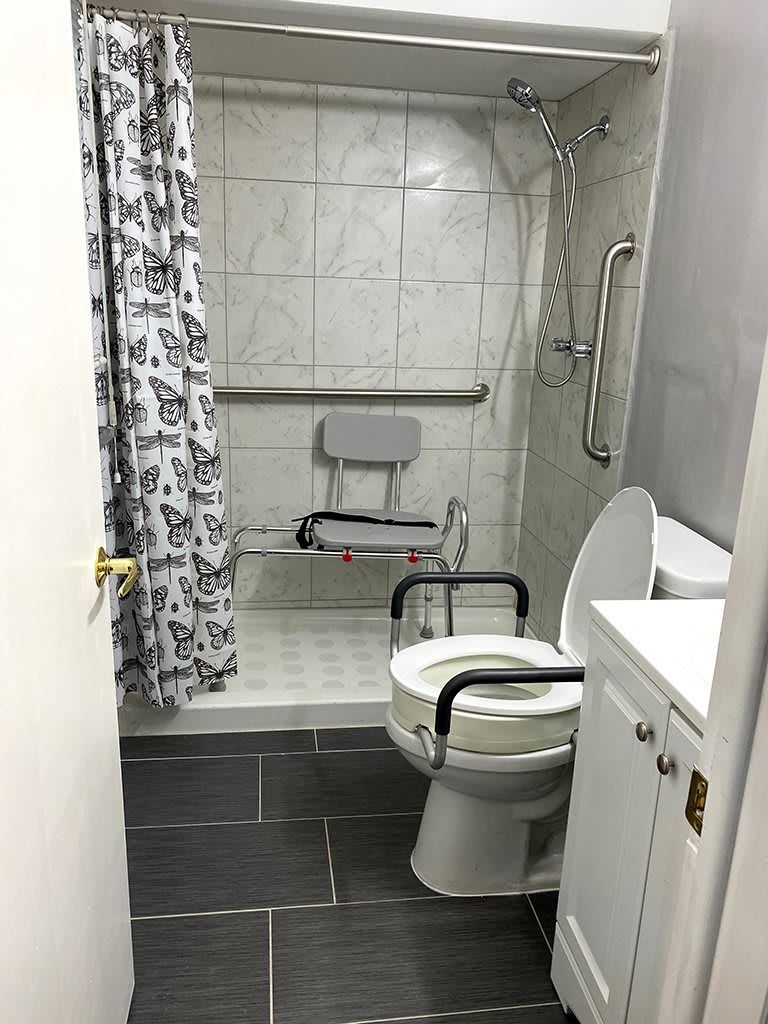 An accessible bathroom with a shower chair and grab bars for safety.