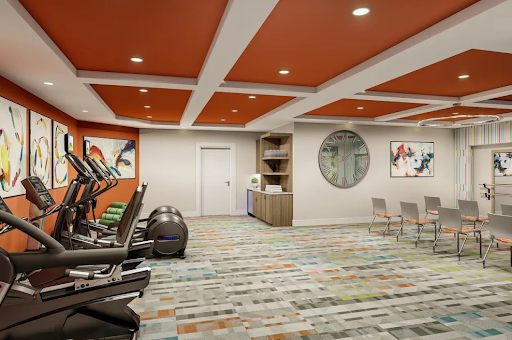A modern gym interior featuring exercise equipment, vibrant ceiling color, and stylish decor.