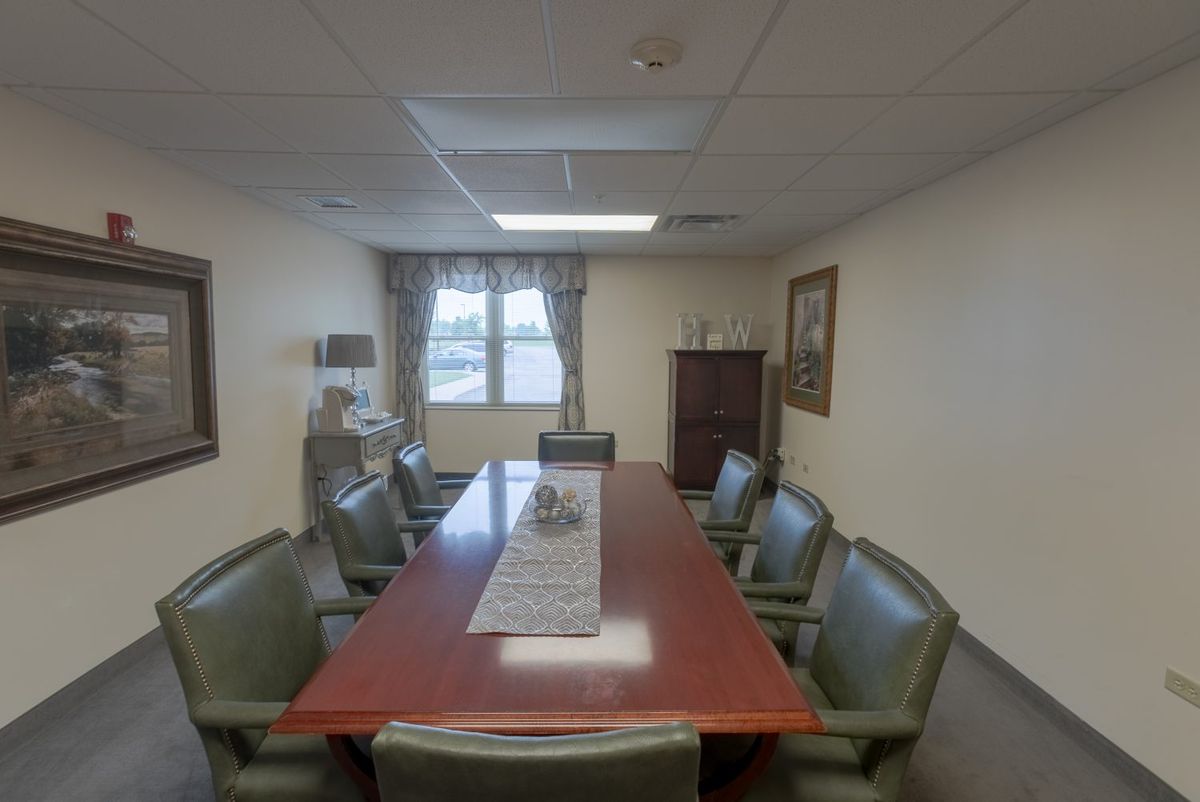 A conference room with a large meeting table and several chairs, featuring a window view and decorative elements.