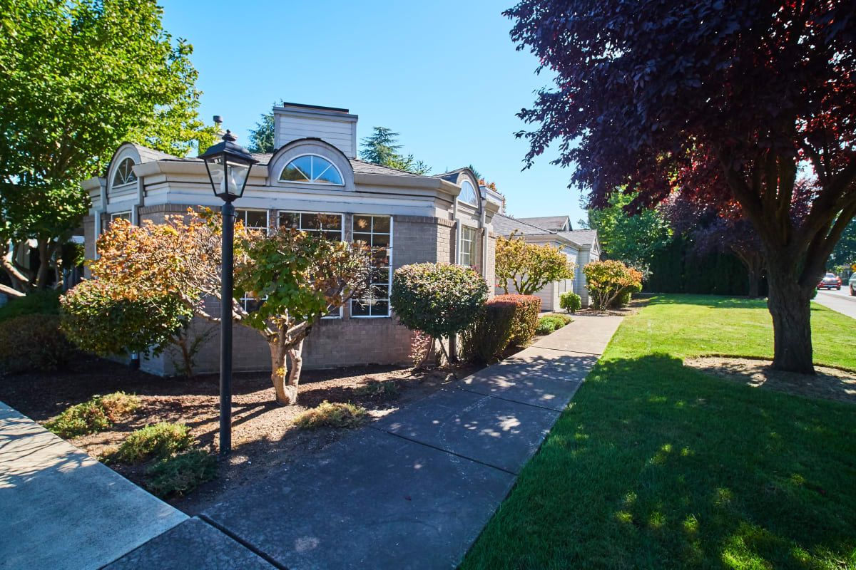 A charming residential house surrounded by well-maintained landscaping on a sunny day.