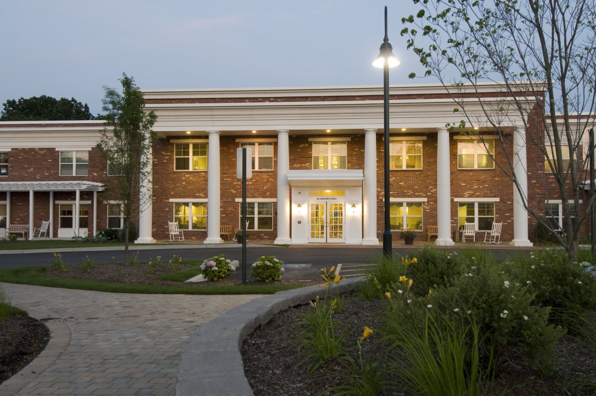 A colonial-style brick building with large columns, illuminated in the evening.