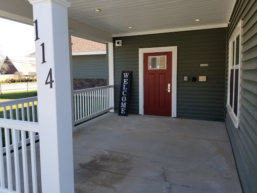 A welcoming front porch with a red door and a welcome sign.