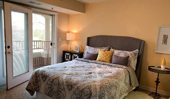 A cozy bedroom with a neatly made bed, decorative pillows, and a lamp on the nightstand.