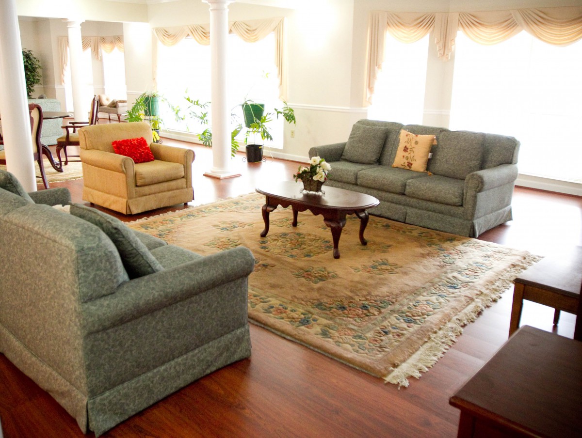 A spacious and well-lit living room featuring comfortable sofas, a central coffee table, and a decorative carpet.