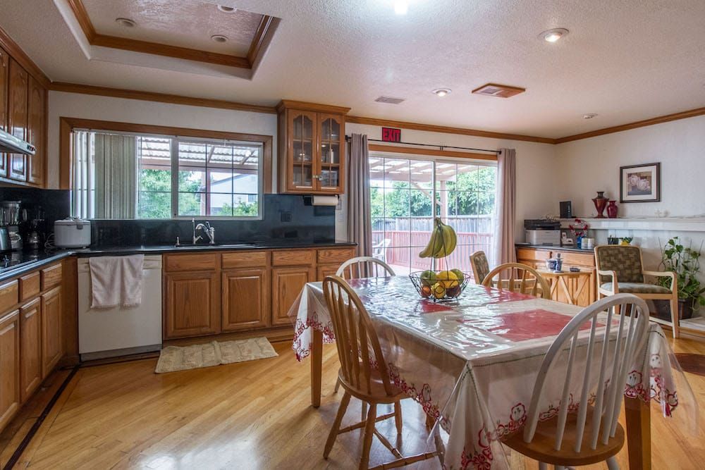 A spacious kitchen and dining area with wooden cabinets and large windows allowing natural light.