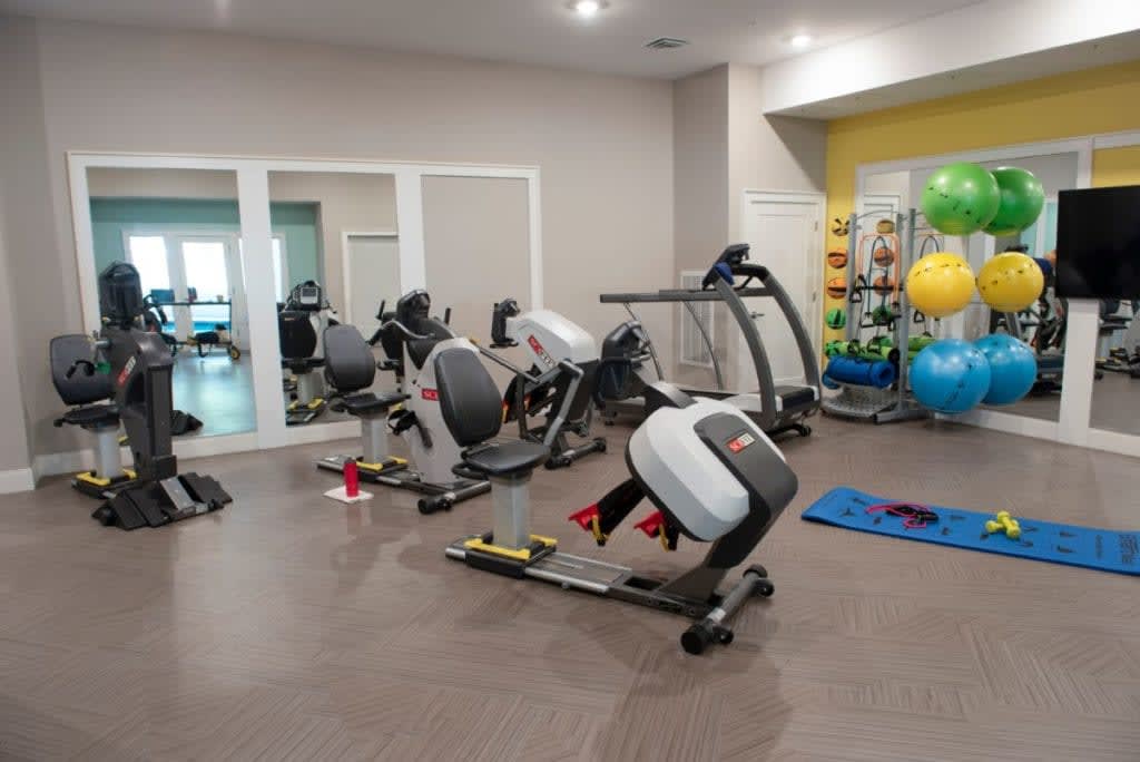 A gym equipped with exercise bikes, a treadmill, yoga mats, and fitness balls.