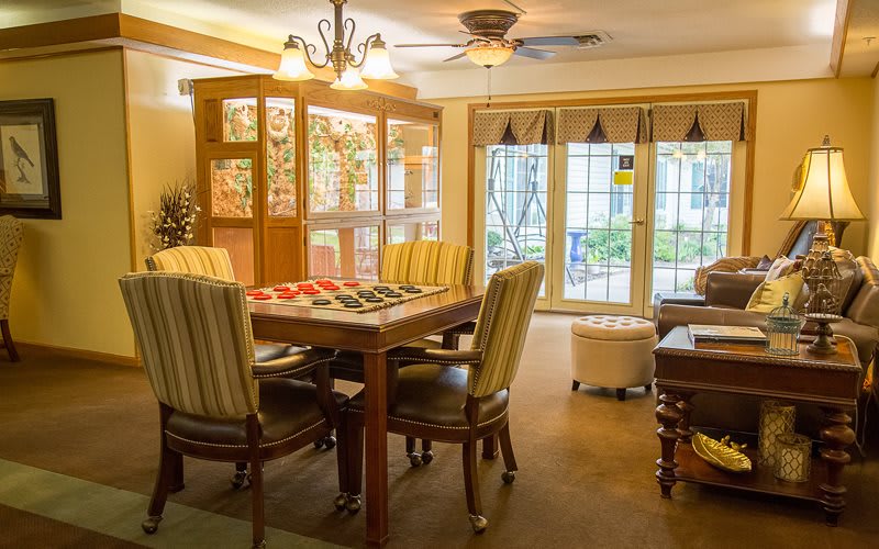 A cozy dining room with wooden furniture and ample natural light streaming through large windows.