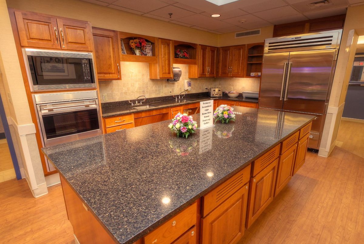 A spacious kitchen featuring granite countertops, wooden cabinets, and stainless steel appliances.