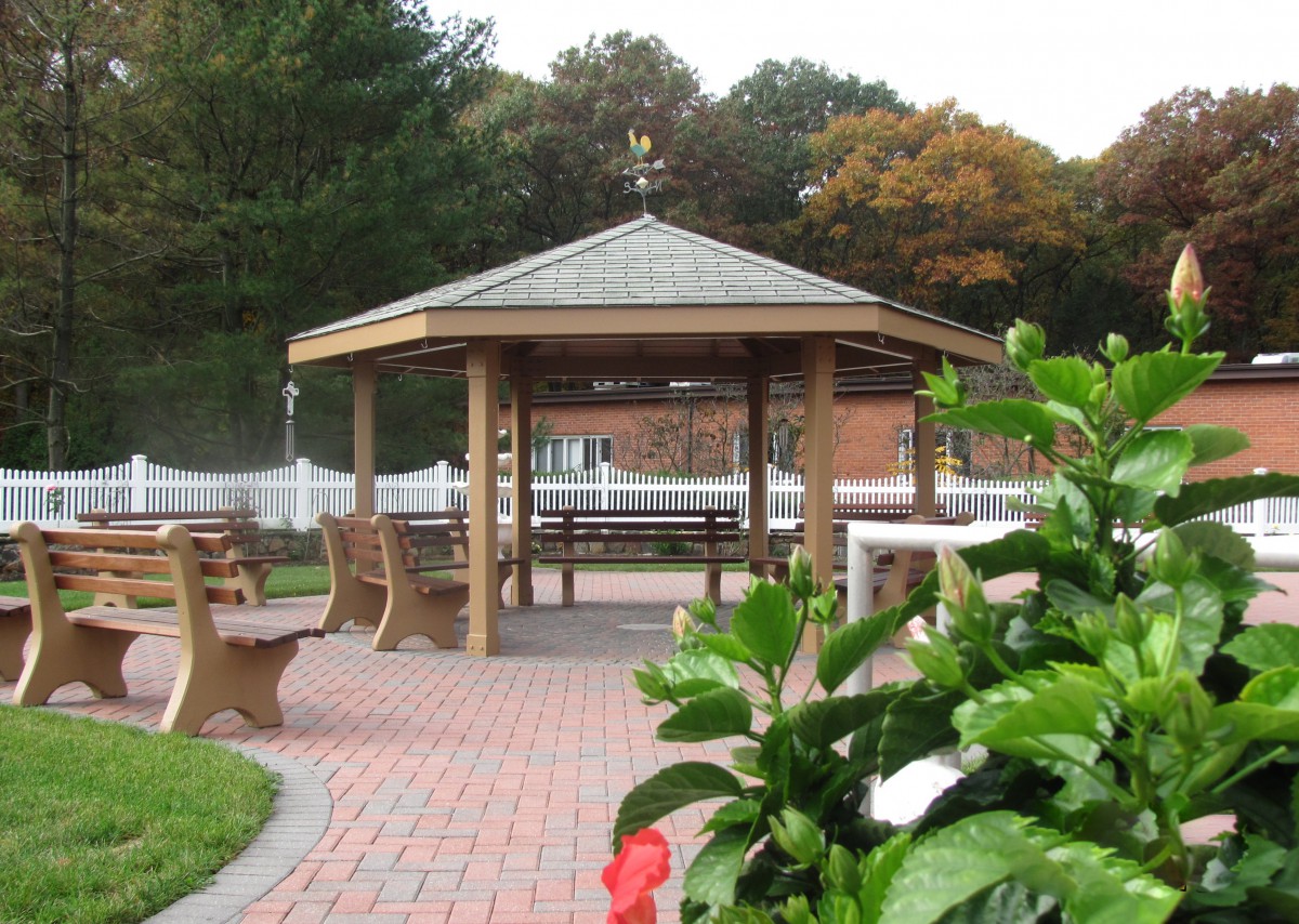 A well-maintained gazebo surrounded by benches and a paved walkway in a park setting.