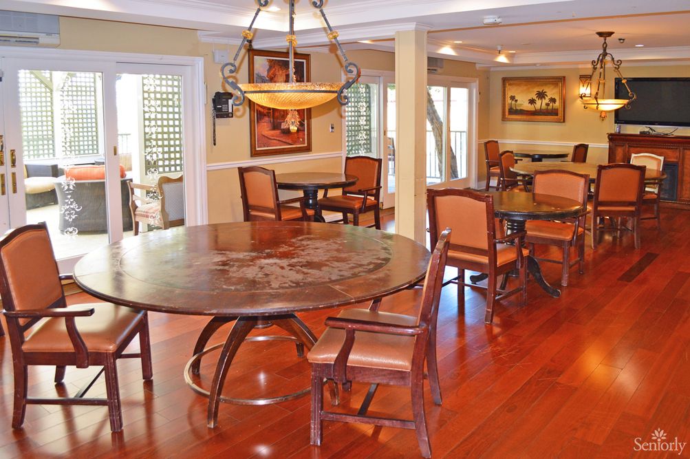 A cozy dining area with wooden floors, round tables, and a classic chandelier.