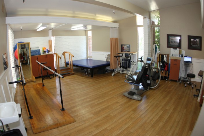 A well-equipped rehabilitation room with exercise machines and therapy tools.