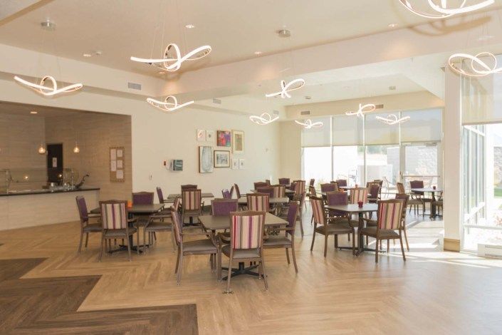 A spacious and elegantly designed dining area with modern lighting and neatly arranged tables and chairs.