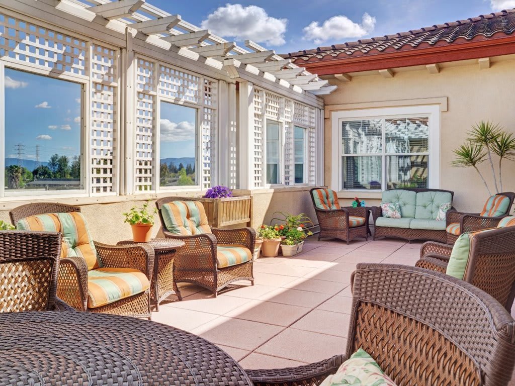 A sunny patio with wicker furniture and decorative plants offers a relaxing outdoor space.